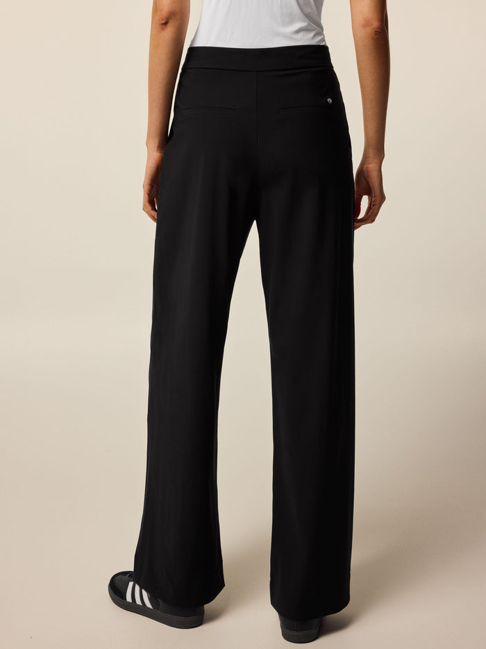 Black Greyson Clothiers Phoenix Wide Leg Pleated Trouser - Back View, Wolf Logo Pin Detail On Model