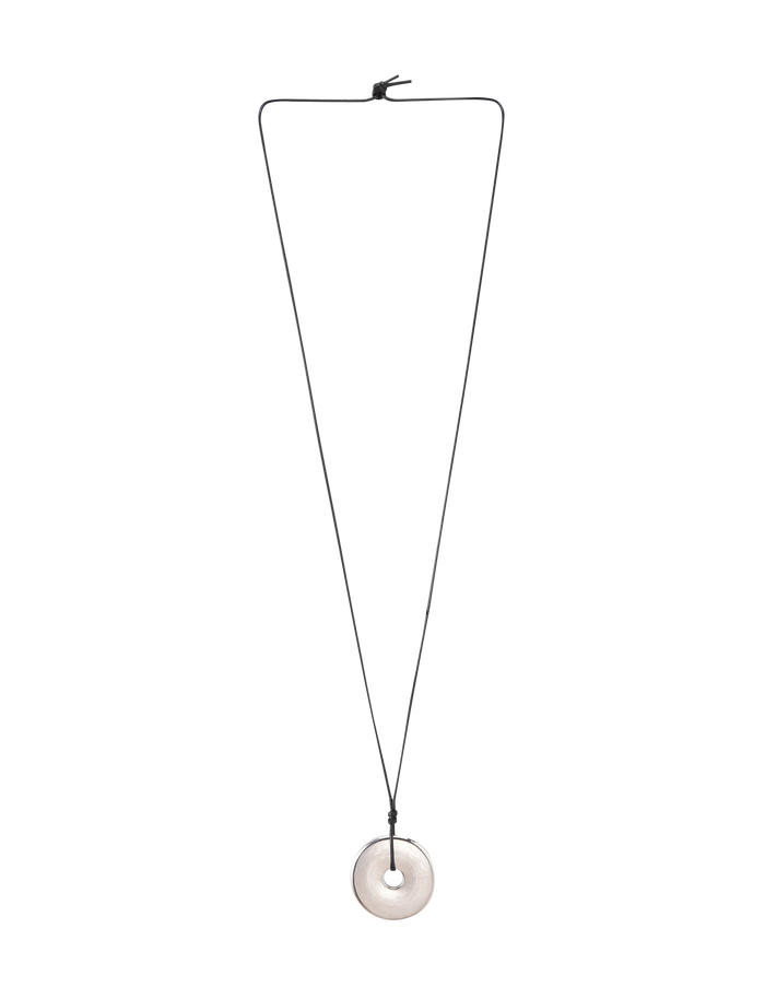 The AIFE PENDANT NECKLACE - SILVER by TIGERMIST features a minimalist design with a black adjustable cord and a round, light stone pendant with a central hole, shown against a plain white background.