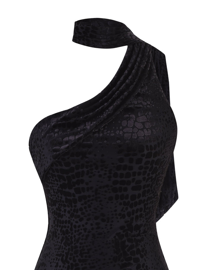 A close-up of the TIGERMIST ALLIRA BURNOUT MINI DRESS 2.0 in black, a one-shoulder dress that showcases a textured, snake-skin-like pattern. The dress elegantly drapes over the shoulder with a velvet burnout finish, offering an exquisite and sophisticated appearance.