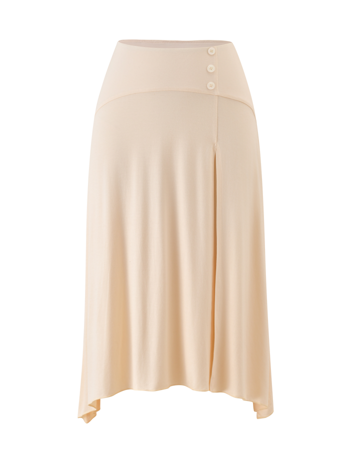 The TIGERMIST ALYSSA HI LO SKIRT in cream features an asymmetrical hem, front leg slit, wide waistband with three side buttons, and soft, flowing fabric for effortless elegance.