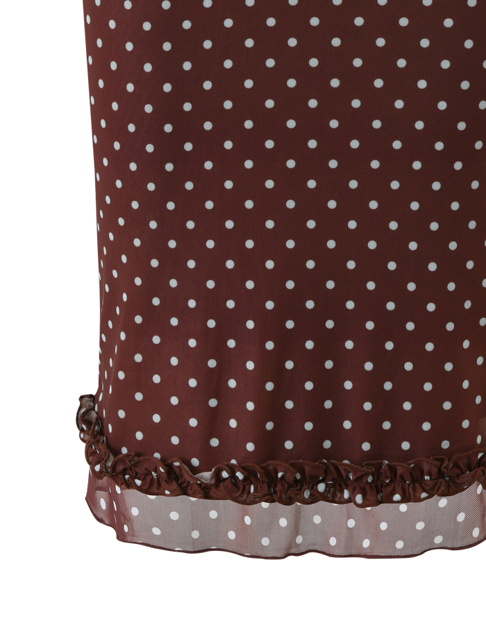 A close-up of the TIGERMIST AMARA MIDI SKIRT - POLKA DOT, showcasing its brown fabric with white dots and a charming ruffled hem.