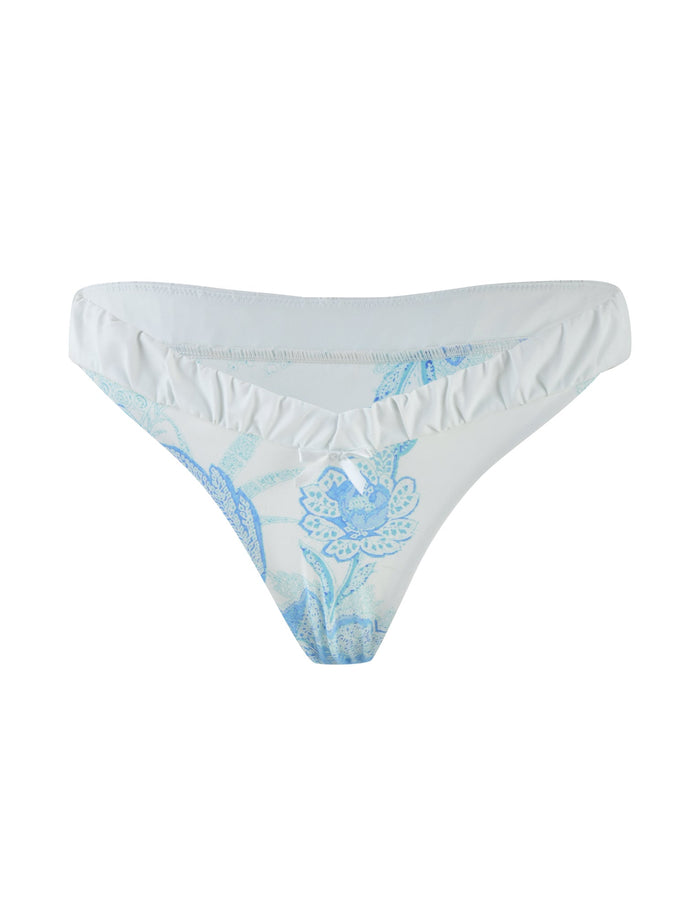 The AMARAN BIKINI BOTTOM - BLUE : FLORAL TAPESTRY by TIGERMIST features a trendy bikini brief style with white fabric adorned with a light blue floral pattern and a ruffled section at the waistband.