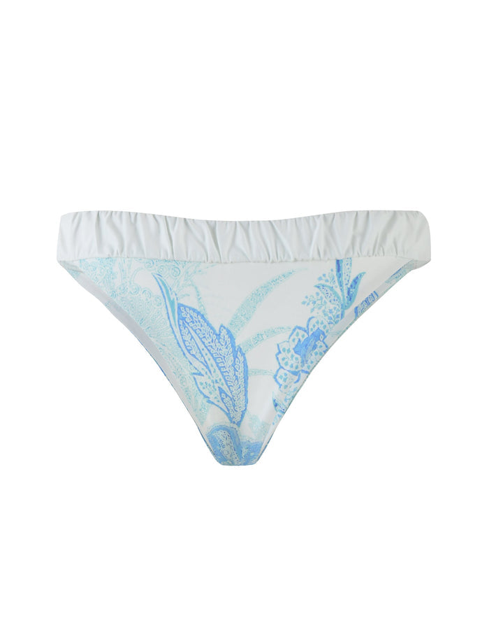 The AMARAN Bikini Bottom from TIGERMIST features a light blue floral tapestry pattern on a white background, crafted in a flattering bikini brief style. The slightly ruffled waistband enhances the bodycon fit, adding a delightful touch of charm.