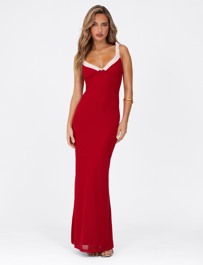 A woman with long, wavy hair poses gracefully against a white background, wearing the TIGERMIST AMARAN MAXI DRESS - RED : BURGUNDY, a bodycon silhouette featuring white lace-trim straps.
