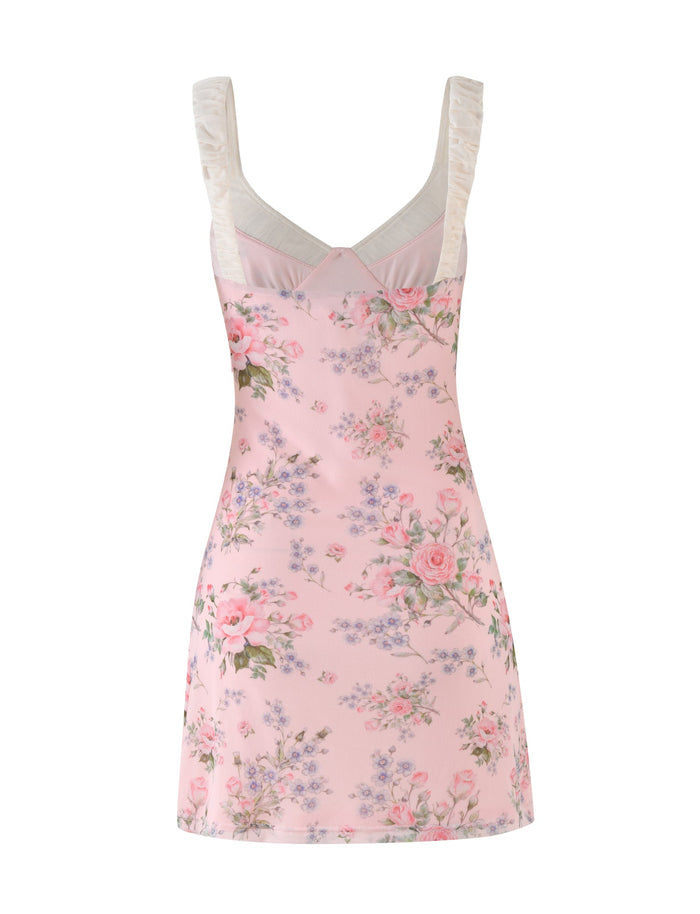 The AMARAN MINI DRESS - PINK : FLORAL : WILD FLOWER by TIGERMIST is a sleeveless piece with ruffled shoulder straps, showcasing a subtle bustier style. It features a pattern of roses and small flowers in shades of pink, green, and lavender for a soft and delicate design.