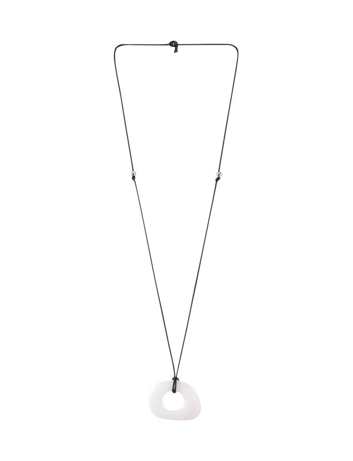 The AMYRA PENDANT NECKLACE - WHITE by TIGERMIST is a long, minimalist necklace with a white asymmetrical resin pendant and hole detail, suspended on a black waxed cord and shown against a plain white background.