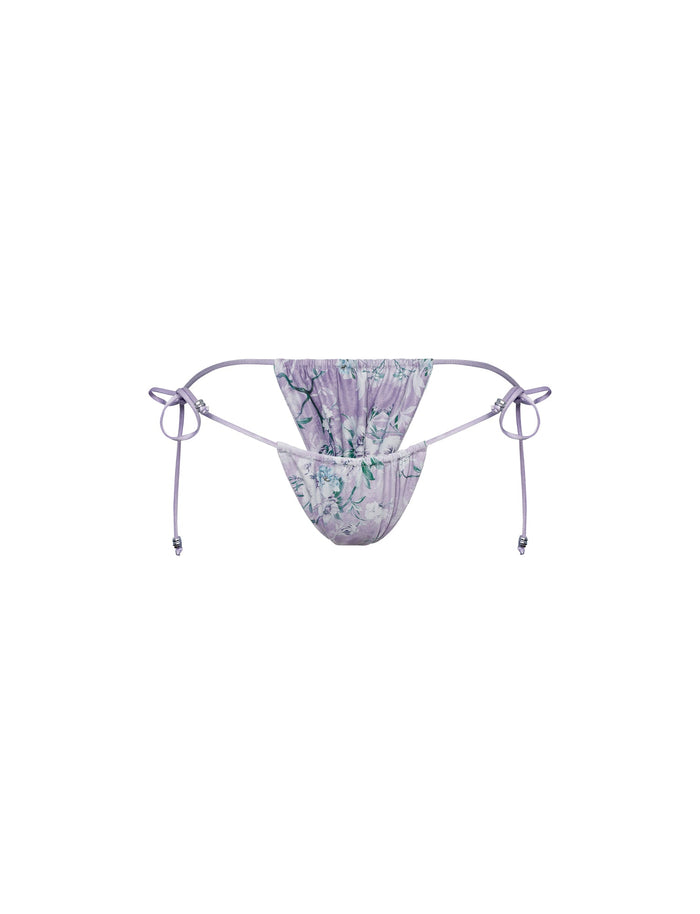 The TIGERMIST AVE BIKINI BOTTOM in Purple: Floral Boarders features a cheeky fit and adjustable side ties, shown on a white background.