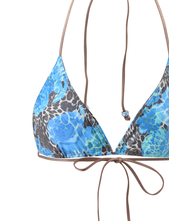 The AVE BIKINI TOP - BLUE LEOPARD by TIGERMIST features a halter neck silhouette, thin brown straps, a front-tied bow, and a close-up look at its unique blue floral and brown leopard print patterns.