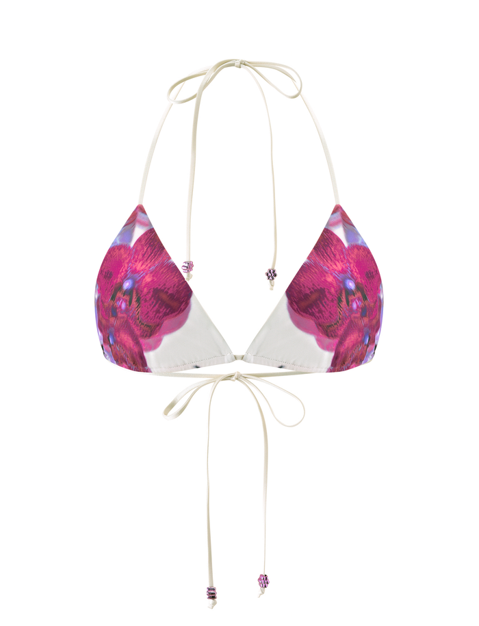The AVE BIKINI TOP – ORCHID HAZE by TIGERMIST is a triangle bikini top with thin cream straps, a pink floral orchid haze print, and beaded accents on the neck and back tie ends.