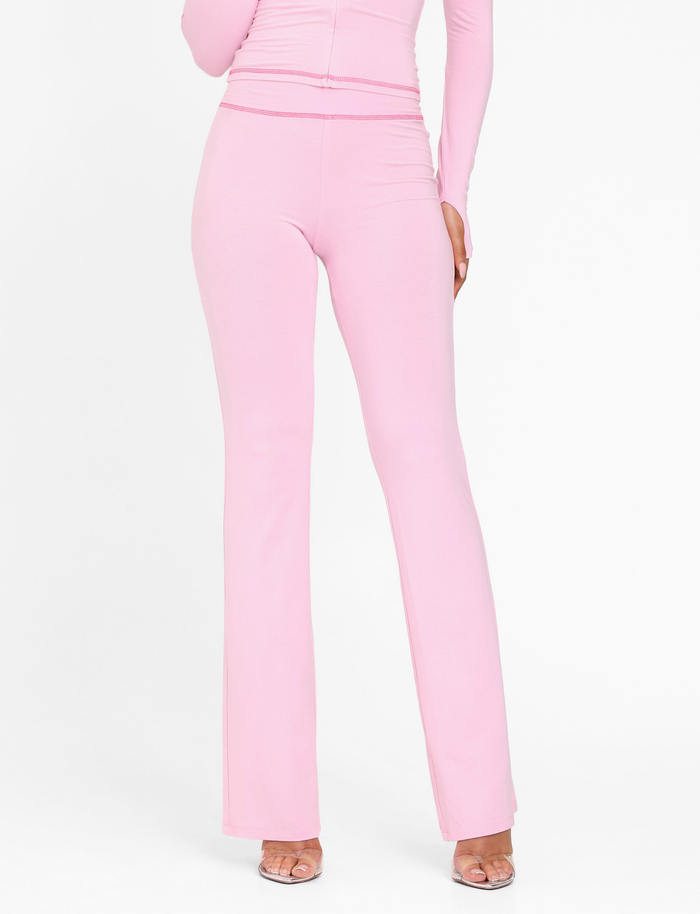 A person wearing TIGERMIST's BLAYZE PANT in soft pink with a matching long-sleeve top and clear open-toe heels, cropped from shoulders down against a white background.