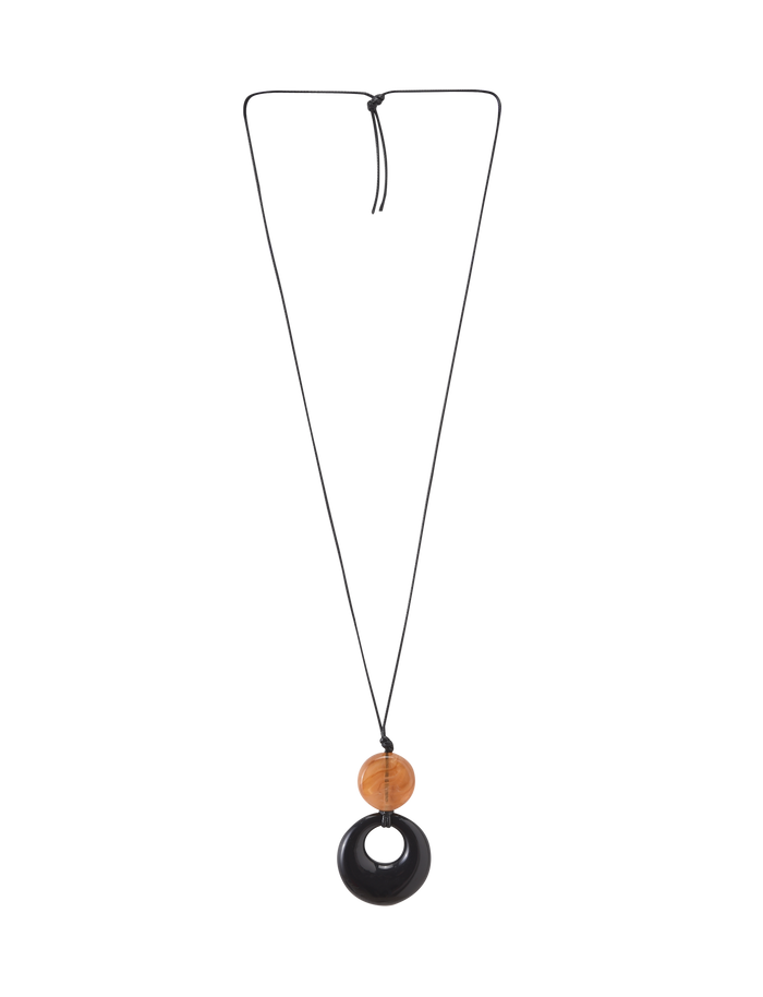 The TIGERMIST BREYA PENDANT NECKLACE - TAN features a minimalist long black cord with a round brown tortoiseshell bead and a larger black resin pendant.