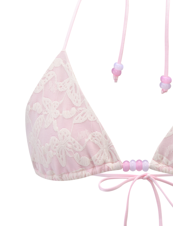 The BRIGITTE BIKINI TOP by TIGERMIST features an ivory lace overlay, beaded straps, an adjustable halter neck tie, and a small center bow for a delicate look.