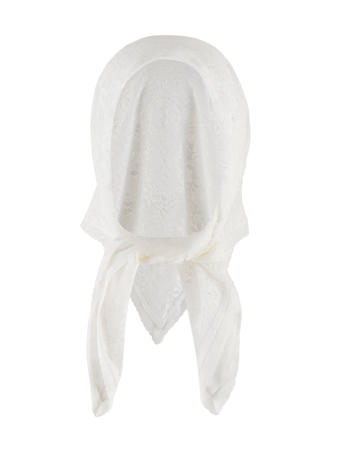 A woman is wearing a strapless, white lace top and a brown, ruffled mini skirt. She has long, wavy dark hair and is accessorized with rings, a bracelet, and the elegantly draped BRIONY SCARF - WHITE by TIGERMIST. The background is plain white.