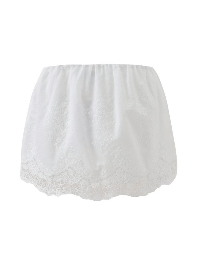 The CAILEIGH MINI SKIRT - WHITE by TIGERMIST features lace detailing, a scalloped hem, and floral embroidery, shown against a plain white background.