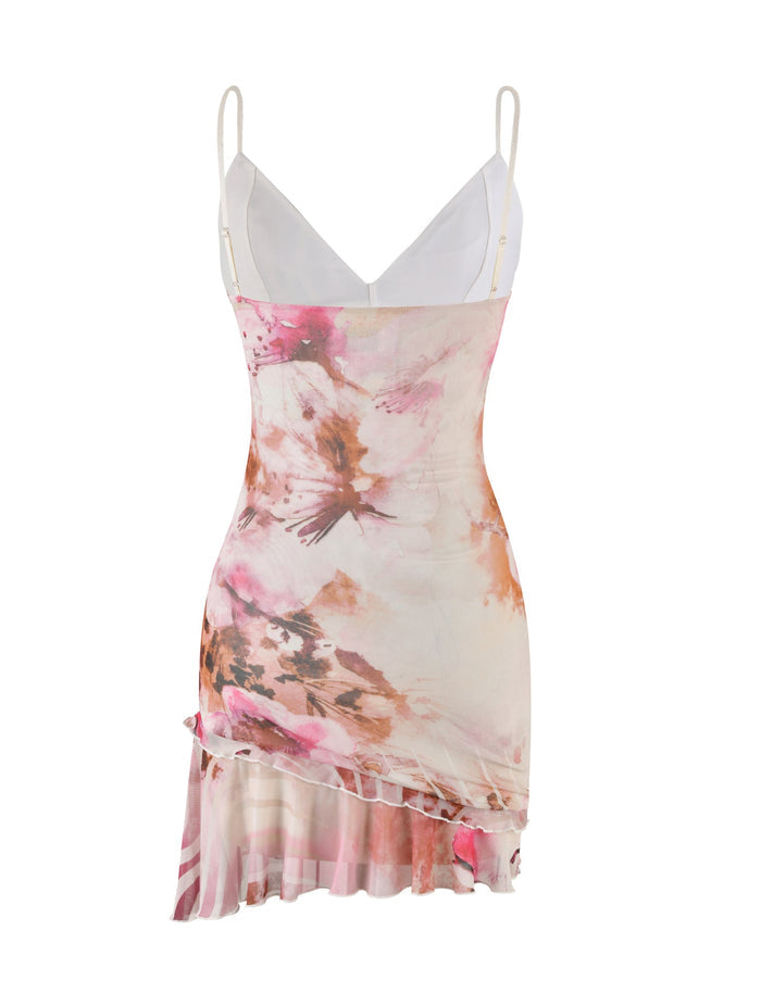 The CARLY DRESS - MULTI : FLORAL by TIGERMIST is a fashionable sleeveless dress that boasts a floral print, thin straps, and a plunging neckline. This sophisticated piece features a pastel pink and orange color palette, complemented by a fitted bodice and an asymmetrical hem with flowing ruffles.