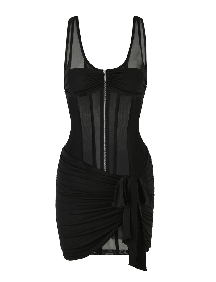 The TIGERMIST CATERINA MINI DRESS - BLACK is a sleeveless mesh mini dress with a sheer bodice, scoop neckline, front zipper, and ruched skirt with an asymmetrical draped tie detail over a slinky jersey lining.