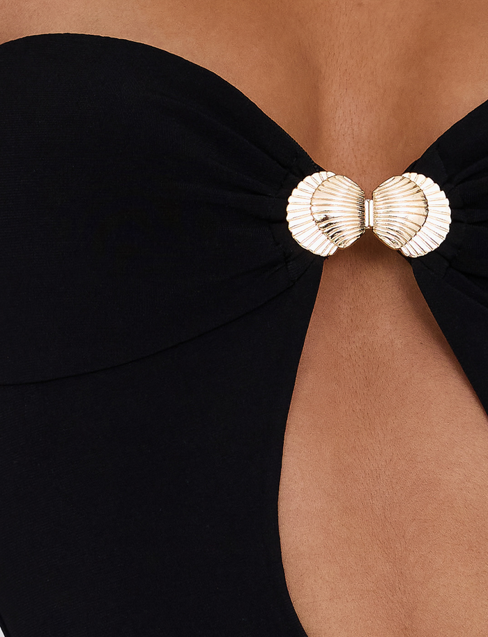 Close-up of the TIGERMIST CECILY MAXI DRESS in black, featuring a strapless design with gathered fabric at the bust and a gold seashell clasp at the center, revealing a glimpse of skin.