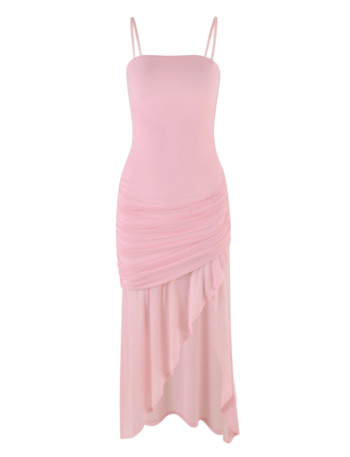 The BABY PINK COVE DRESS by TIGERMIST is a light pink, sleeveless dress with thin shoulder straps that showcases a fitted bodice and elegant ruched detailing around the waist and hips. Its cascading, asymmetrical skirt falls to mid-calf length and is crafted from soft, flowy fabric.