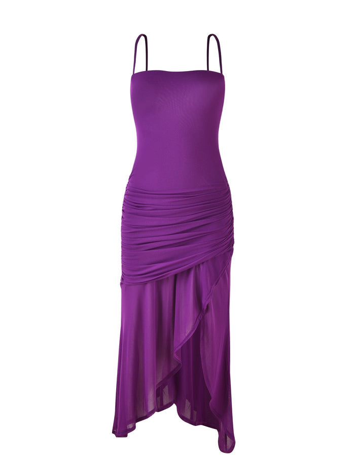 The COVE DRESS - PURPLE by TIGERMIST is a stylish and elegant sleeveless dress. It features spaghetti straps, a fitted bodice, gathered fabric details at the waist, and an asymmetrical hem with flowing layers.