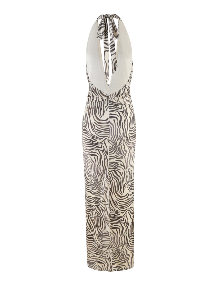 The CRESSIDA DRESS - NEUTRAL : ZEBRA by TIGERMIST is a sleeveless halter neck dress with a bold zebra print, plunging neckline, deep V-shaped open back, and a long straight silhouette.