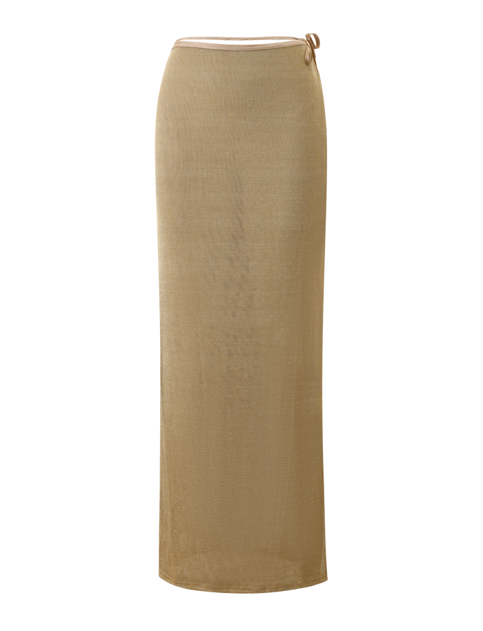 The TIGERMIST CYRENE TIE MAXI SKIRT in gold is a long, fitted, semi-sheer metallic knit skirt featuring a high waist and a small tie detail at the waistband, shown against a plain white background.