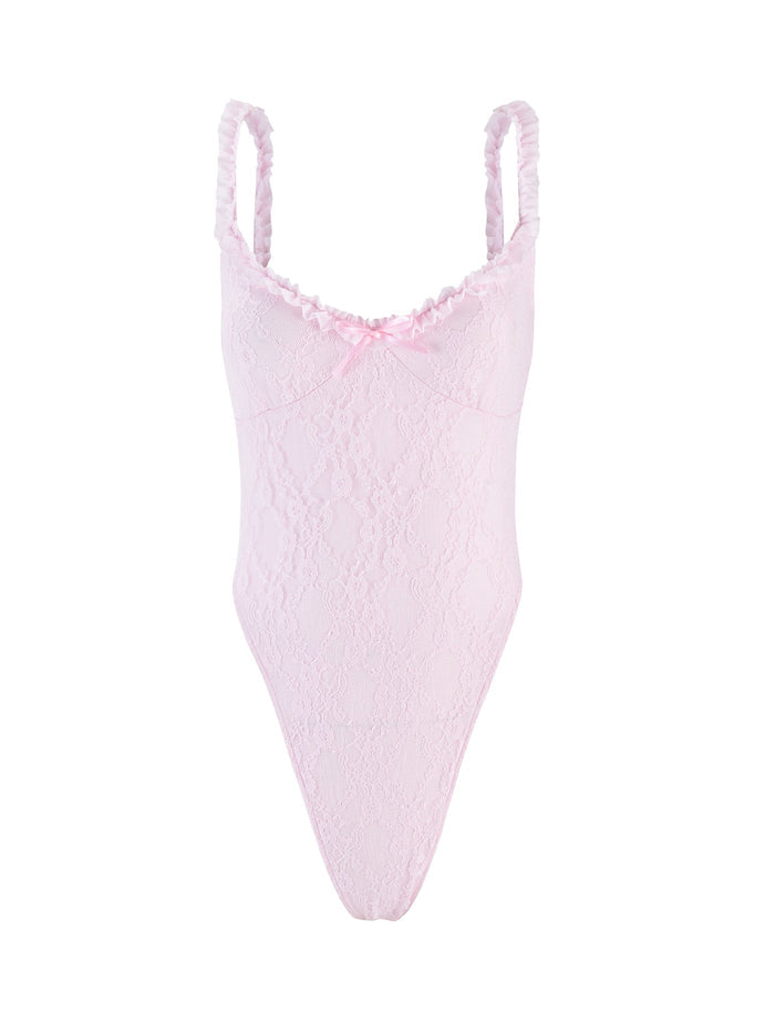 The DEJA BODYSUIT in pastel pink from TIGERMIST features thin shoulder straps, a delicate ruffle trim around the neckline, and a small bow at the center. Its high-cut leg design adds a stylish touch to this light pink lace bodysuit.