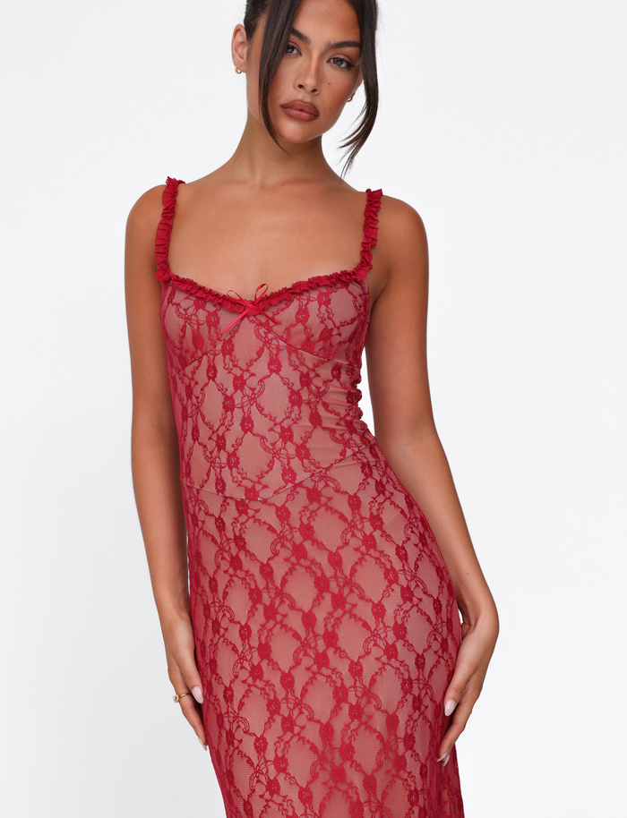 A woman models the TIGERMIST DEJA DRESS - RED: BERRY RED, a sleeveless, semi-sheer lace dress with ruffled straps and a fitted silhouette, standing against a plain white background with her dark hair styled in a loose updo.