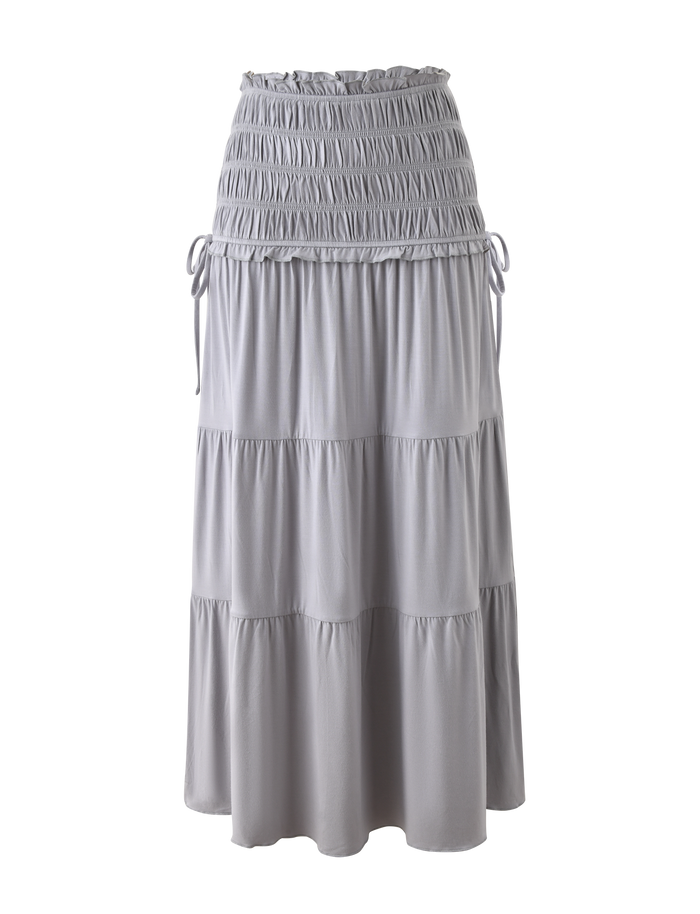 The TIGERMIST DENALI MAXI SKIRT in Dove Grey features soft modal fabric, a shirred elastic waistband with drawstring ties, and gathered, tiered layers for a flowy look. Shown against a plain white background.