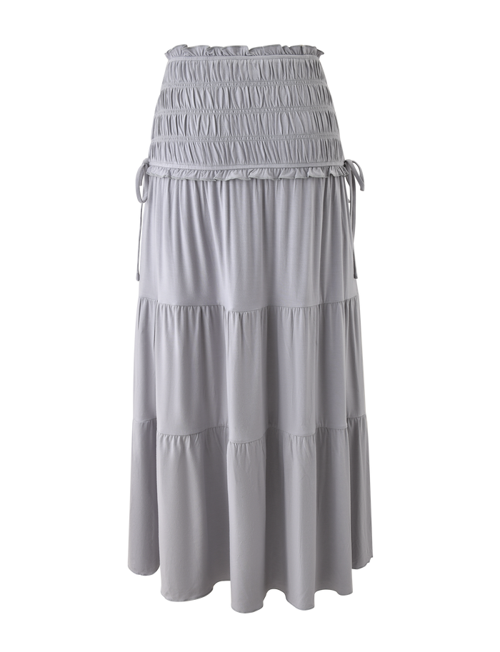 The TIGERMIST DENALI MAXI SKIRT in Dove Grey features soft modal fabric, a shirred waistband, tiered layers, adjustable side ties, and a flowy, relaxed fit with gathered texture for easy style.