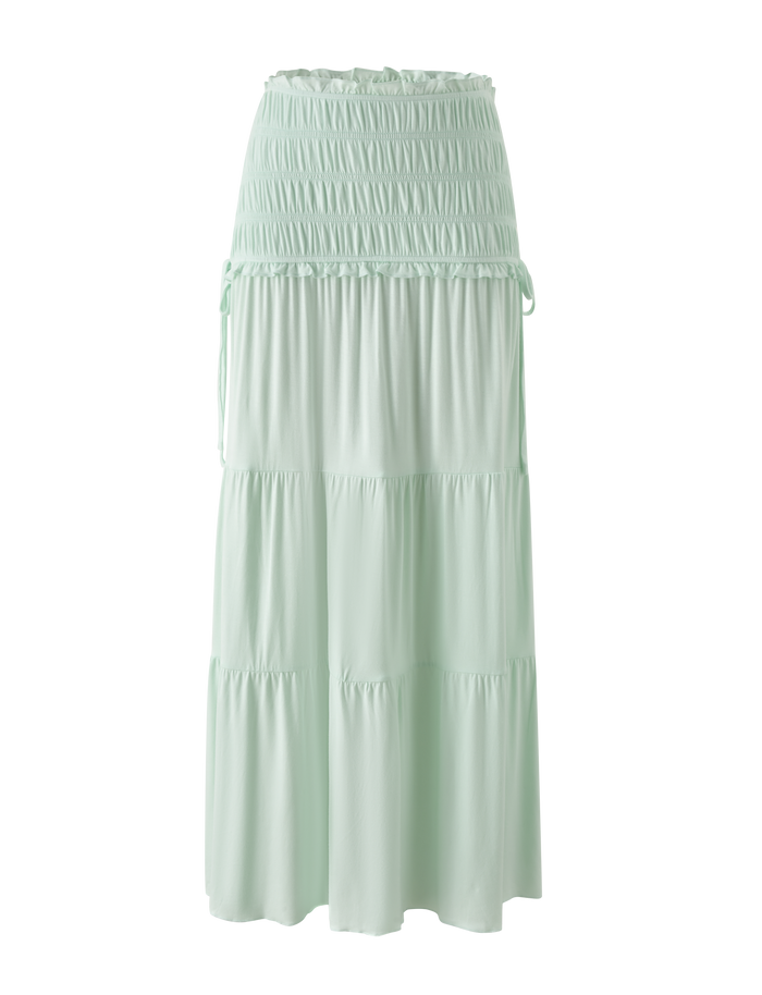 The DENALI MAXI SKIRT - SOFT MINT by TIGERMIST is a light mint green maxi skirt in soft modal, with a wide shirred waistband and adjustable side ties, shown against a plain white background.