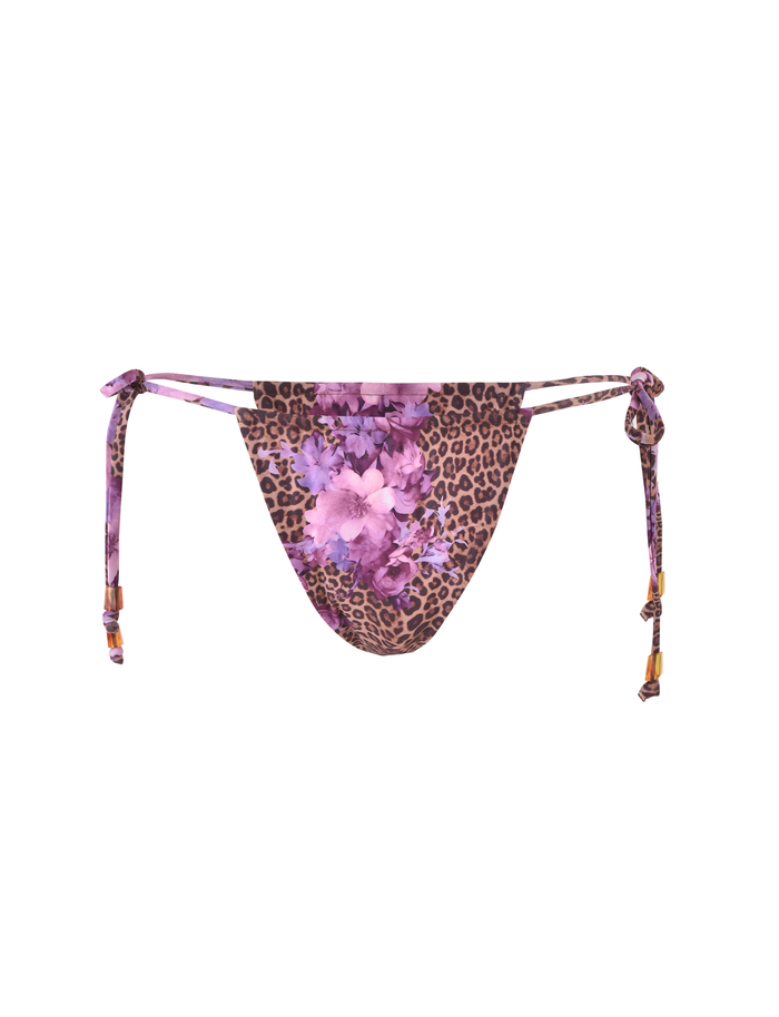 The DESIRAE BIKINI BOTTOM by TIGERMIST features a purple, floral leopard print with adjustable side ties and wooden bead accents for a customized fit.
