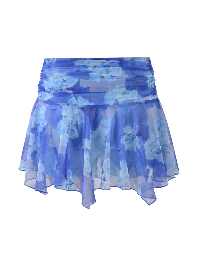 The DEVYN MINI SKORT by TIGERMIST features a blue macro floral print, sheer stretch fabric, asymmetrical handkerchief hem, and a gathered waistband.