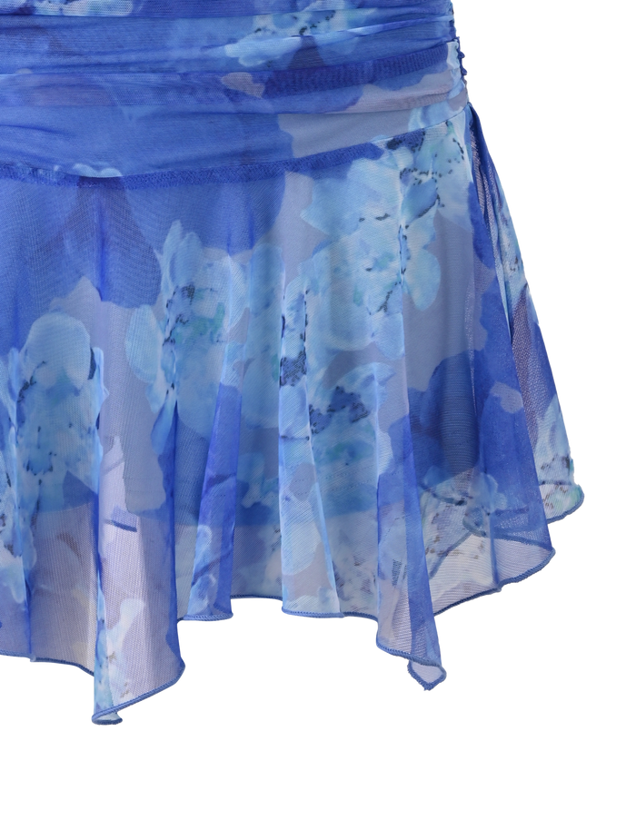 The DEVYN MINI SKORT - BLUE MACRO FLORAL by TIGERMIST is a blue, floral-printed handkerchief mini skort made from lightweight stretch fabric, shown against a white background.