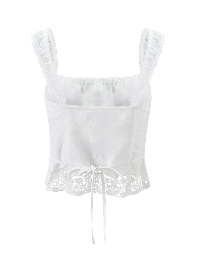 The ELENAI TOP - WHITE by TIGERMIST is a white lace tank with a ruched bust, wide straps, square neckline, floral embroidery, and a ribbon tie waist, shown against a plain white background.