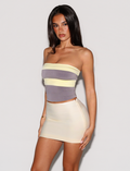 A woman with long, straight dark hair and a neutral expression stands against a white background, wearing the TIGERMIST EOS TOP in grey and yellow—a colour blocked, strapless piece featuring pastel stripes.