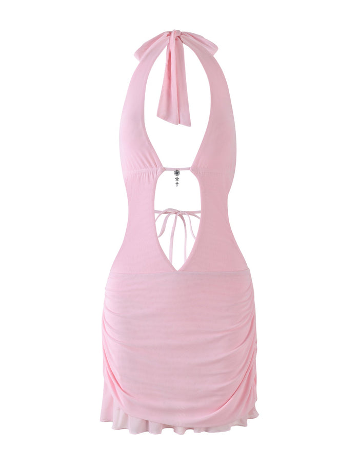 The ESHA DRESS - PINK by TIGERMIST is a baby pink halter mini dress featuring an open back with tie closure, ruched sides, fitted bodycon silhouette, a flowing hem, and a decorative lower back cut-out tie detail.