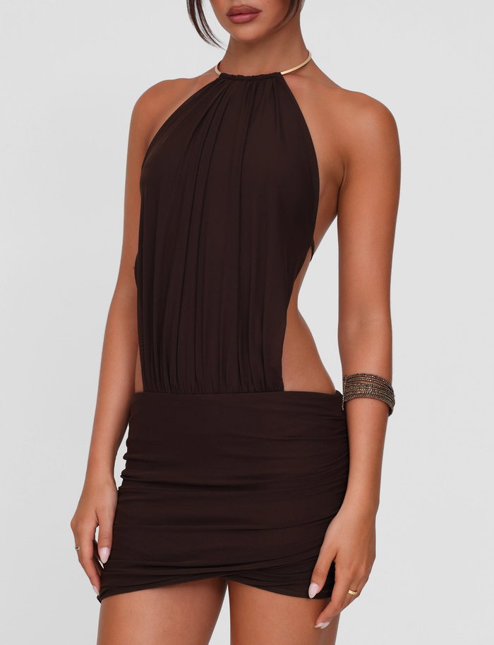 A woman wears the TIGERMIST EVANNA MINI DRESS - BROWN: CHOCOLATE, a bodycon high neck mini with ruched stretch fabric, accessorized with a metallic choker and wide metallic bracelet. Her face is partially out of frame.