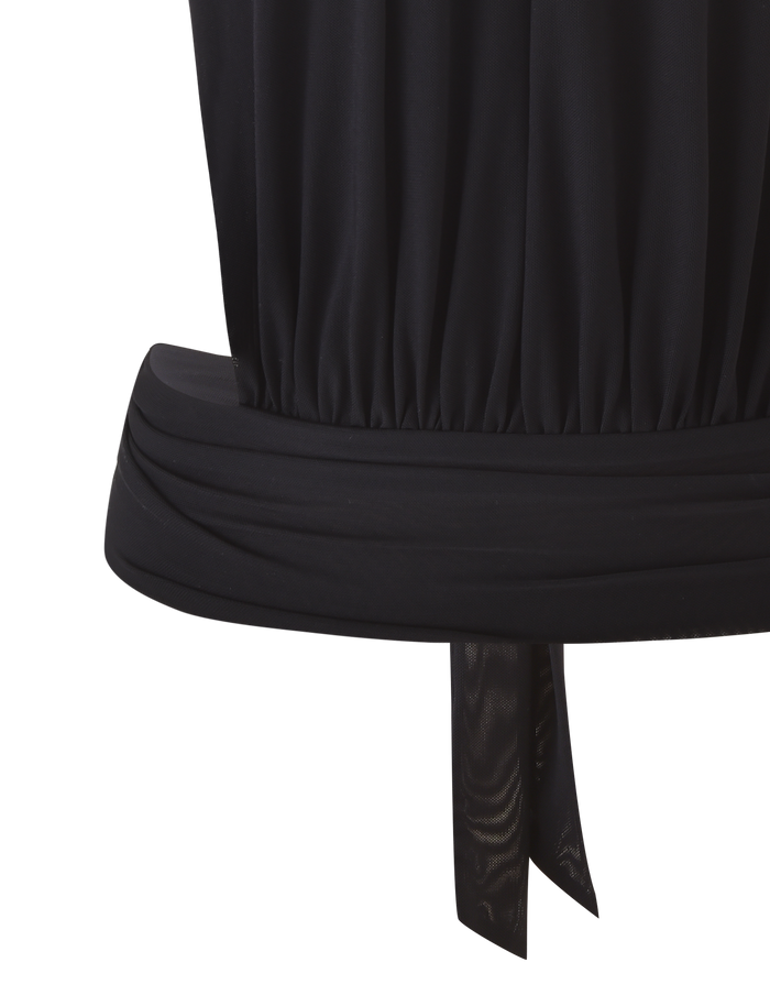 Close-up of the lower part of the EVANNA TOP - BLACK by TIGERMIST, featuring a wide waistband and a tied detail hanging down.