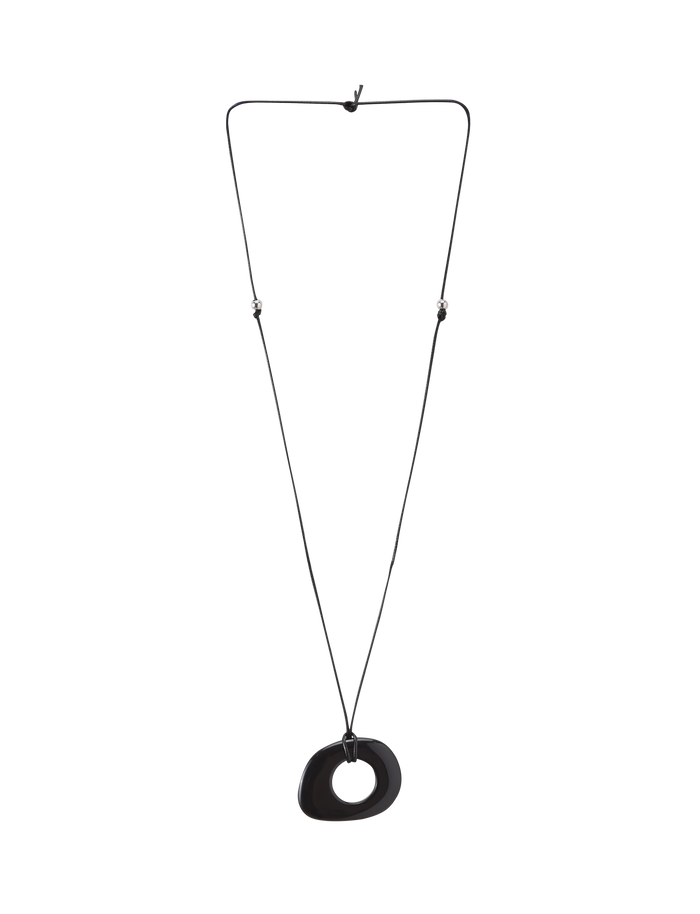 The FAELLA PENDANT NECKLACE - BLACK by TIGERMIST features a minimalist black cord with adjustable length and an abstract, asymmetrical black resin pendant at the center, shown on a white background.