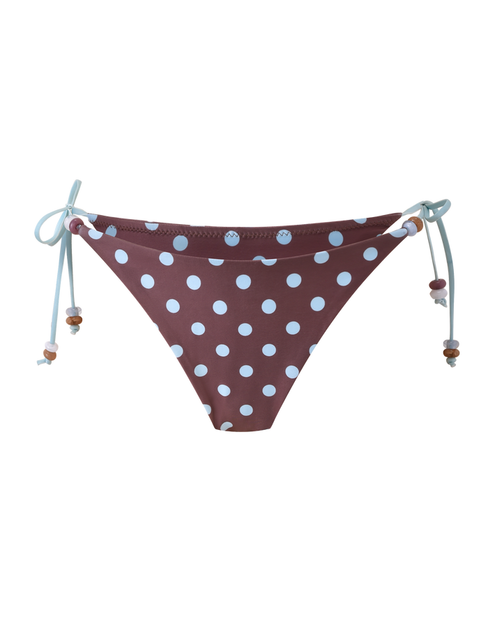 The FINLEA BIKINI BOTTOM by TIGERMIST features a brown and blue polka dot design with light blue side ties and small bead accents for a playful look.