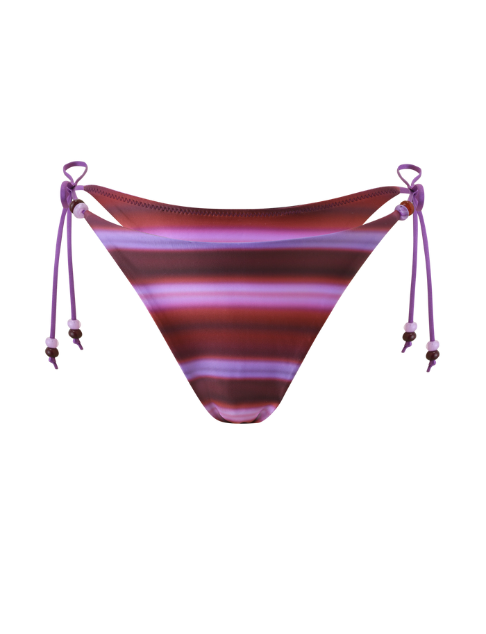 The TIGERMIST FINLEA BIKINI BOTTOM - DUSK OMBRE STRIPE features adjustable side ties with small beads and a cheeky fit in purple, pink, and maroon ombre stripes, shown on a white background.