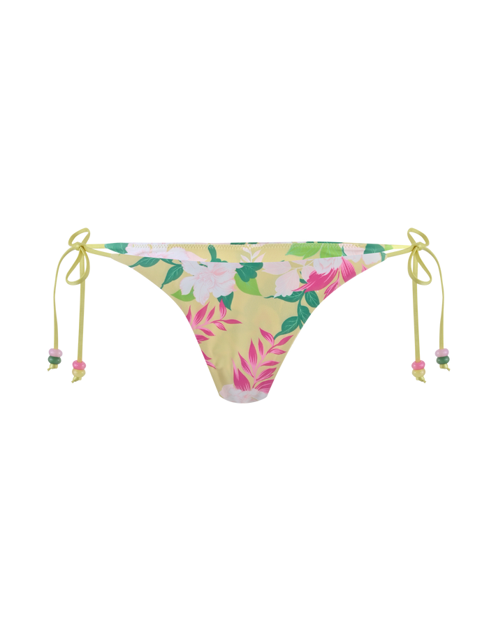 The FINLEA BIKINI BOTTOM - PAISLEY BORDER by TIGERMIST is a yellow bikini bottom with side ties, a cheeky cut, and a vibrant print of pink, green, and white tropical flowers and leaves.