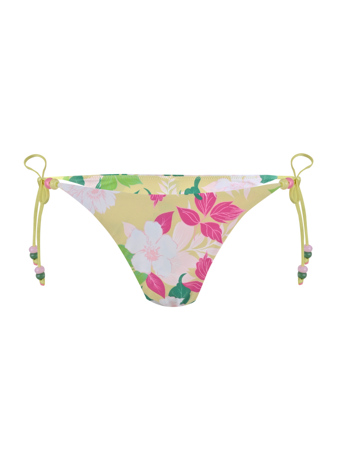 The FINLEA BIKINI BOTTOM - PAISLEY BORDER by TIGERMIST is a yellow cheeky bikini bottom with side ties and a bold paisley floral print in white, pink, and green, crafted from elastane swimwear fabric.