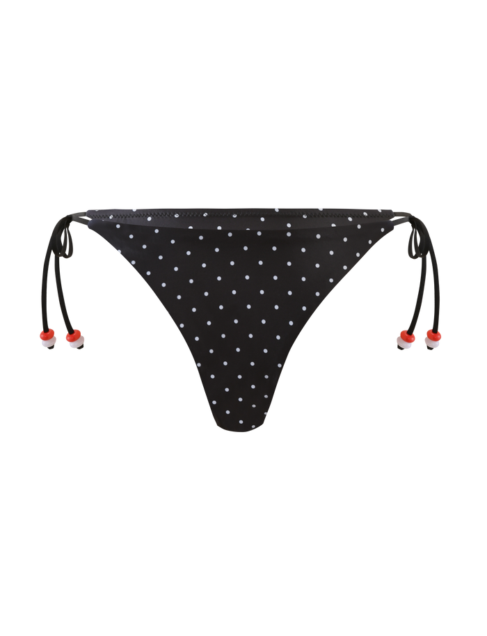 The TIGERMIST FINLEA BIKINI BOTTOM - POLKA DOT BLACK CREAM features cheeky side ties with red bead accents and a black base with cream spots, shown against a plain white background.