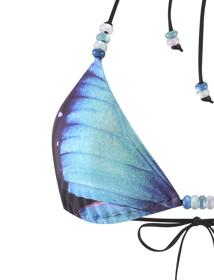The FINLEA BIKINI TOP - BLACK : BUTTERFLY by TIGERMIST is a triangle bikini top with a blue butterfly wing print, halter neck, light blue and white beaded straps, and a black string tie at the bottom.