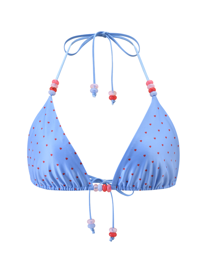 The FINLEA BIKINI TOP - BLUE HEART POLKA DOT by TIGERMIST is a light blue triangle bikini top with heart polka dots, adjustable halter neck, front ties with pink, red, and purple beads. Shown on a plain white background.