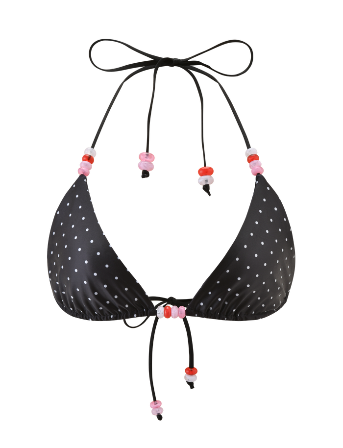 The FINLEA BIKINI TOP - POLKA DOT BLACK CREAM by TIGERMIST features a halter neck design with adjustable black strings, accented by pink and red beads on the ties.