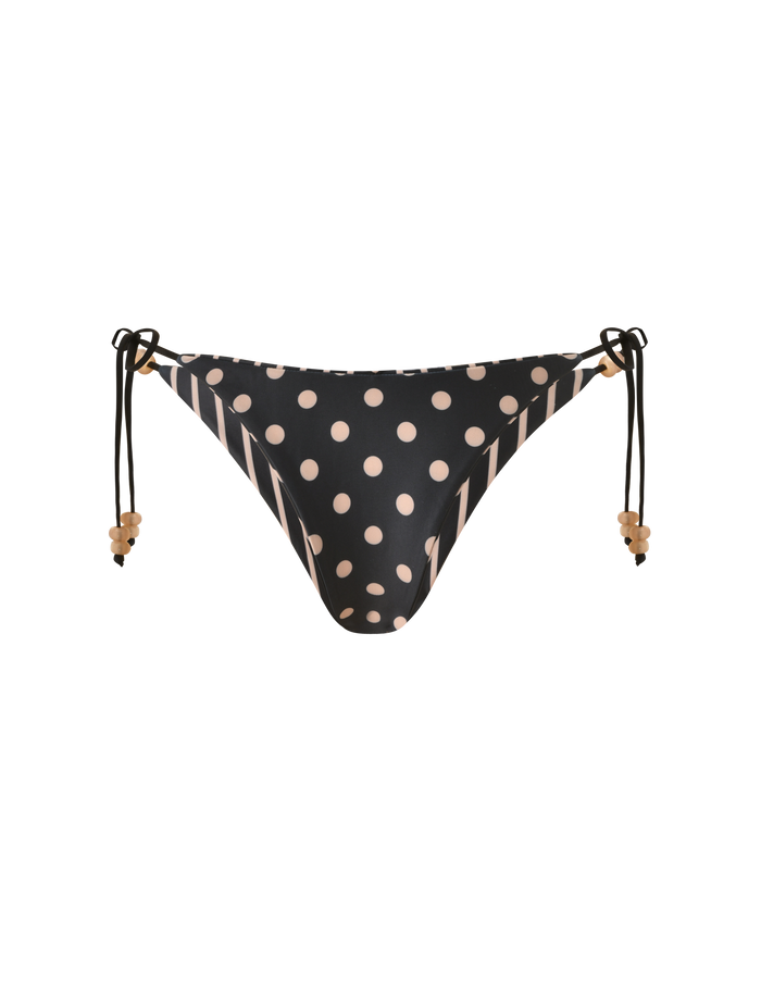 The TIGERMIST FINLEA REVERSIBLE BIKINI BOTTOM features a black cheeky cut with tan polka dots on the front, diagonal stripes on the sides, and adjustable beaded side ties.