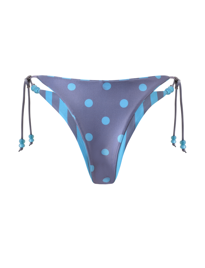 The TIGERMIST FINLEA REVERSIBLE BIKINI BOTTOM in blue grey features dot and stripe patterns, beaded side tie strings, and a cheeky cut with alternating solid and striped sides.