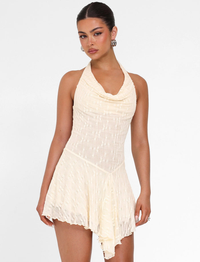 A woman models the TIGERMIST FIORELLA MINI DRESS in cream lace, featuring a halter neck, draped neckline, and asymmetrical hem, against a plain white background.